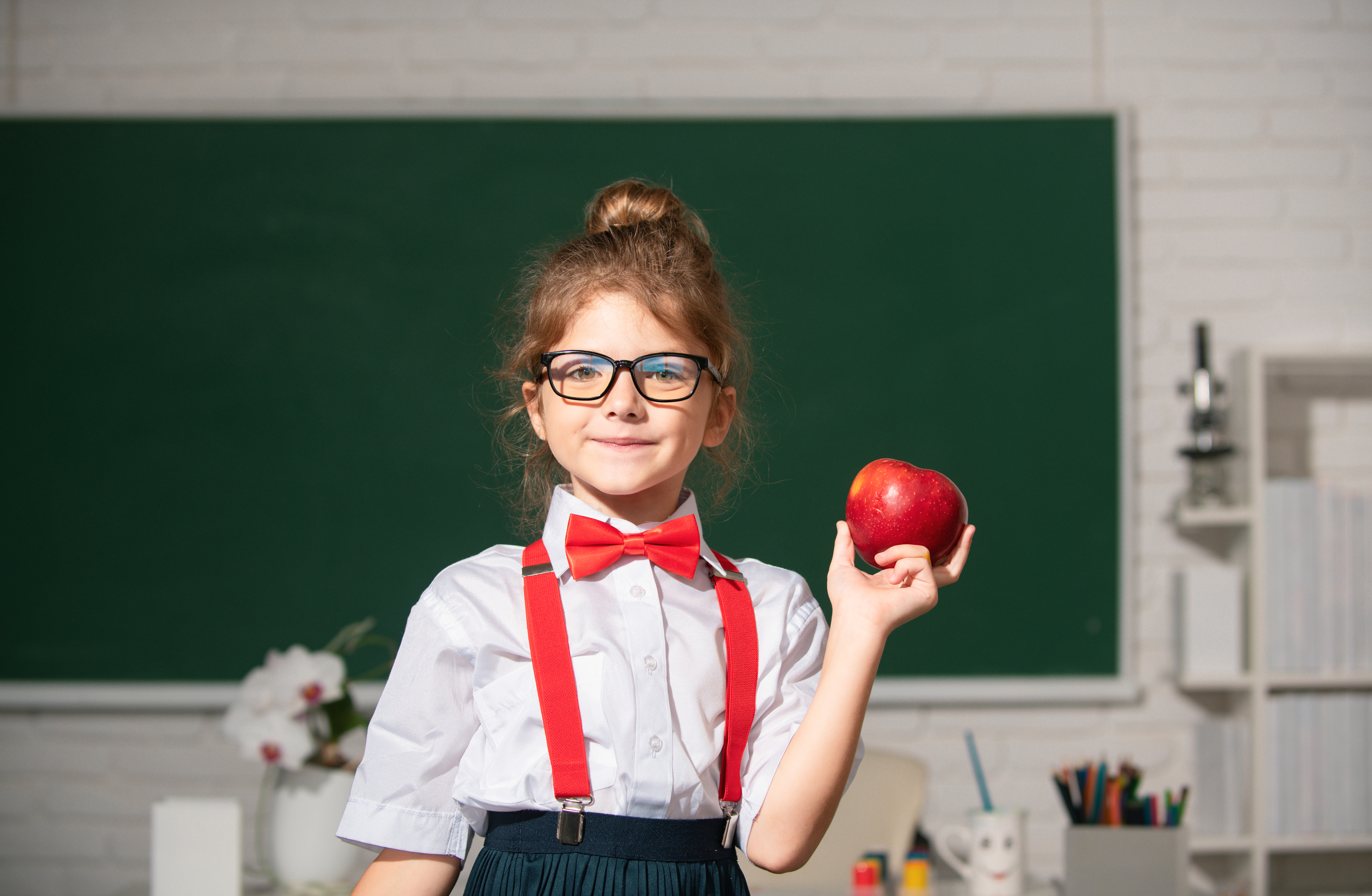 Garota com maçã na mão com uniforme escolar