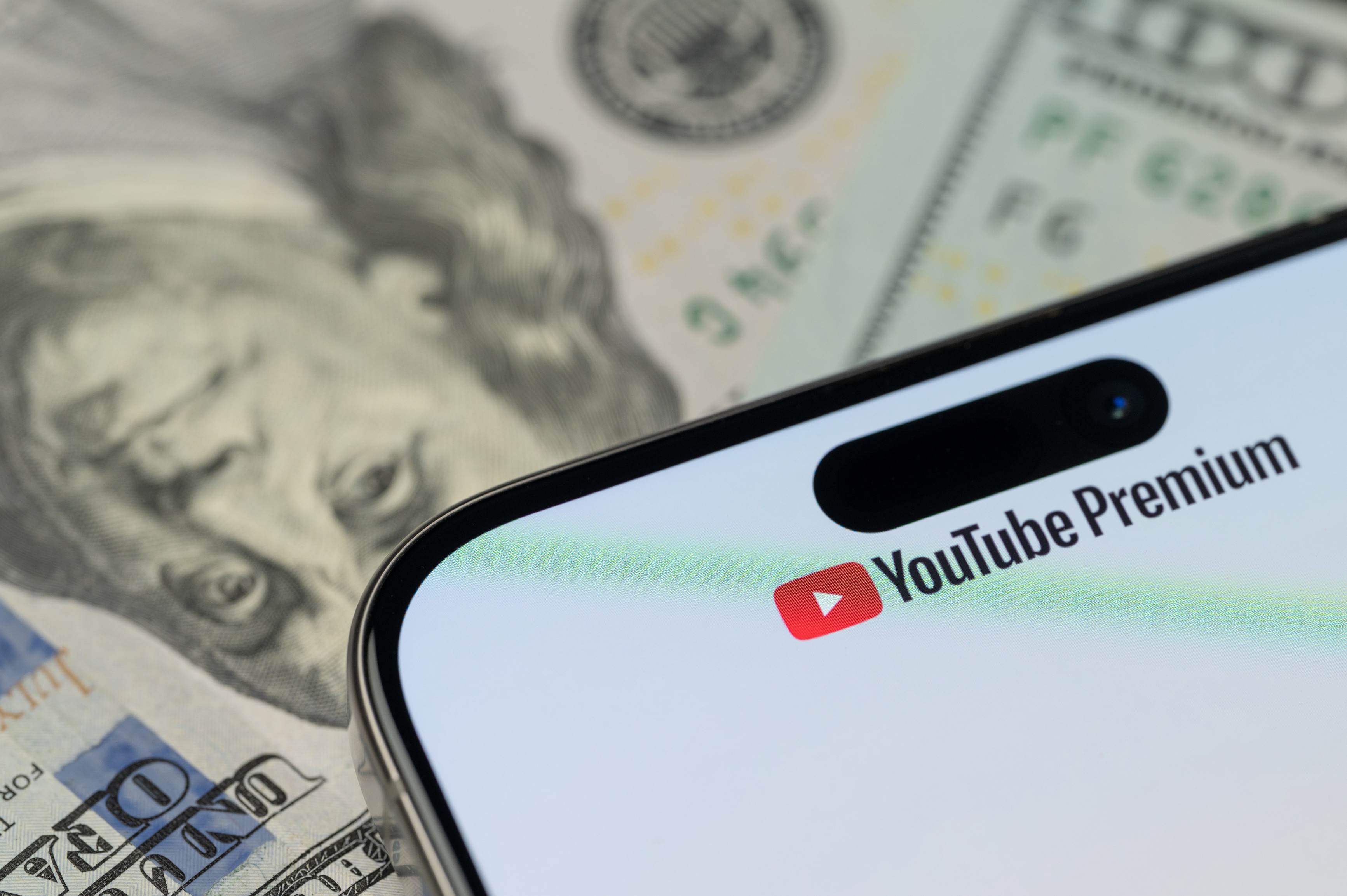 Logo do YouTube Premium em um iPhone sobre notas de dólar